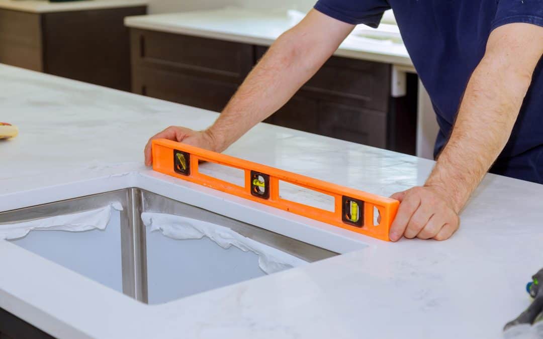 Fabricator leveling a sink cutout with a torpedo level